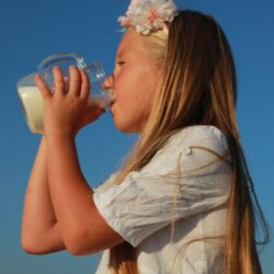 a young girl drinking from a bottle of milk